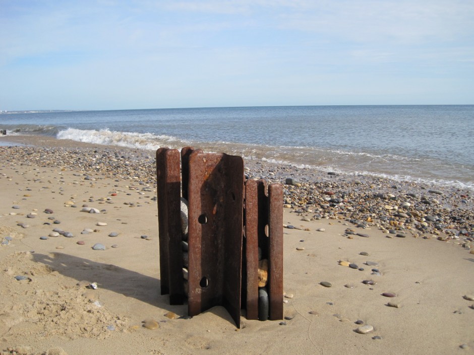 Rusted groynes litter the shore
